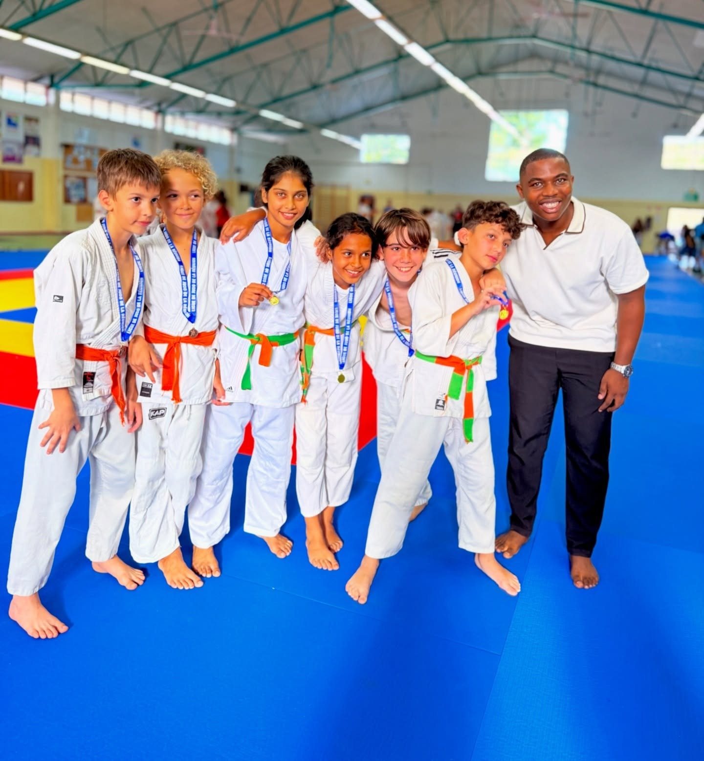 Six jeunes judokas médaillés avec leur enseignant sur le tatami